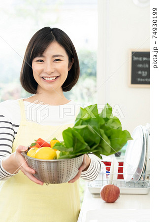 キッチンで野菜を持つ女性 キッチンで野菜を持つ女性 74930199