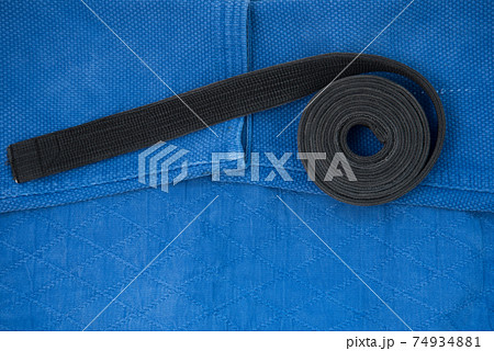The view from the top. Kimono for judo classes and a black belt. The kimono is blue. Background, texture. The view from the top. Kimono for judo classes and a black belt. The kimono is blue. Background, texture. 74934881