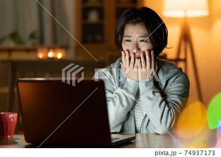 深夜ホラー映画を見る若い女性の写真素材