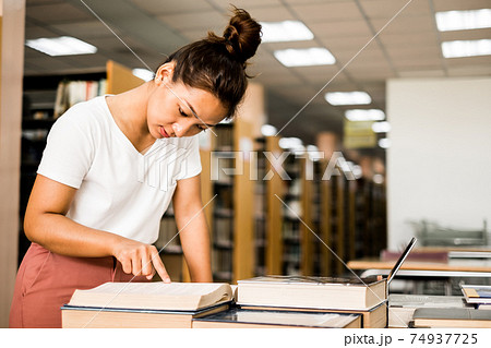 Young Asian women are searching for books and reading from the bookshelves in the college library to research and develop themselves in education 74937725