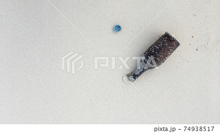 【海洋漂着ごみ】白い砂浜に流れ着いたビンとペットボトルの蓋 74938517
