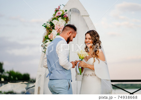 happy newlyweds exchange rings. beautiful wedding ceremony by water on dock.  74938668