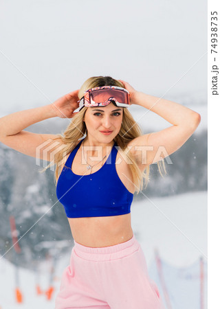 Happy girl snowboarder posing in sunglasses with snowboard Happy girl snowboarder posing in sunglasses with snowboard 74938735