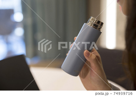 オフィスでミニボトルを使う若い女性手元 74939716