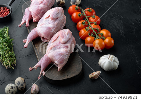 Fresh raw meat quails with herbs, on black textured background Fresh raw meat quails with herbs, on black textured background 74939921
