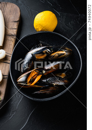 Steamed mussels in black bowl on black concrete surface, flat lay Steamed mussels in black bowl on black concrete surface, flat lay 74940072