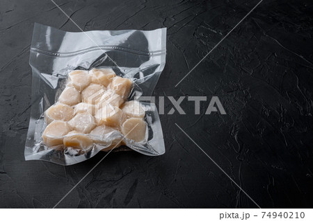 Scallops in vacuum pack, on black textured background with copy space Scallops in vacuum pack, on black textured background with copy space 74940210