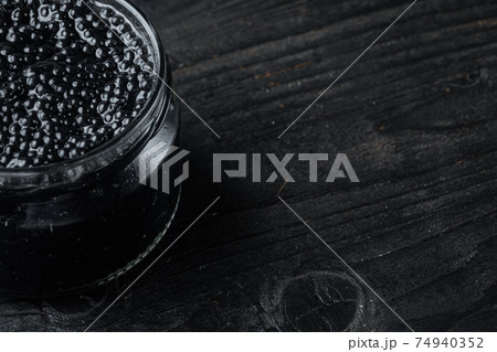 Jar of black caviar, on black wooden table background with copy space for text 74940352