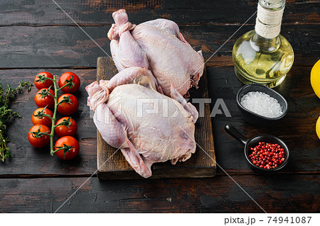 Raw small young chicken with ingredients, on old wooden table Raw small young chicken with ingredients, on old wooden table 74941087