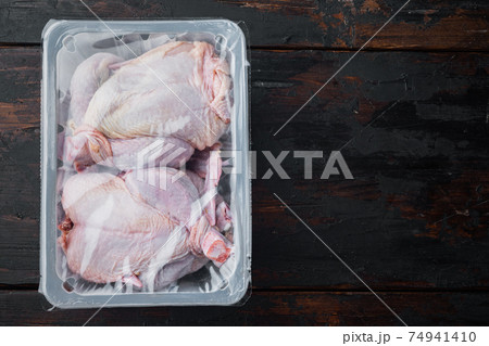 Raw chicken in plastic vacuum tray, on old wooden table, top view with copy space for text 74941410
