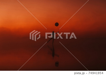 silhouette of a girl practicing a yoga exercise in a pose on the water 74941954