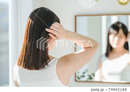 鏡の前で髪をなびかせる女性 鏡の前で髪をなびかせる女性 74942188