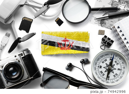 Flag of Brunei and travel accessories on a white background. Flag of Brunei and travel accessories on a white background. 74942996