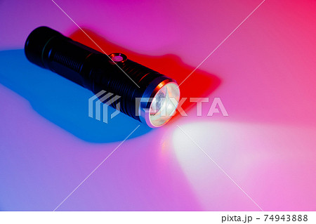 A small black flashlight in colored lighting. A small black flashlight in colored lighting. 74943888