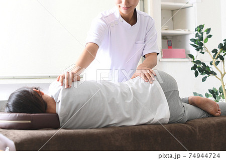 整体(カイロプラクティック)の骨盤矯正中のマッサージを受ける女性 整体(カイロプラクティック)の骨盤矯正中のマッサージを受ける女性 74944724