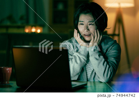 深夜リビングでホラー映画を見て怖がる若い女性 深夜リビングでホラー映画を見て怖がる若い女性 74944742