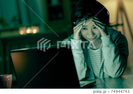 深夜リビングでホラー映画を見て怖がる若い女性 74944743