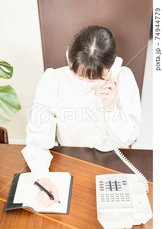 固定電話で仕事の電話をするマスクをした女性 74944779