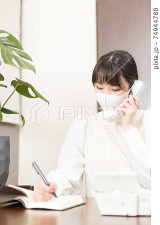 固定電話で仕事の電話をするマスクをした女性 固定電話で仕事の電話をするマスクをした女性 74944780