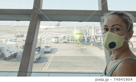 Woman caucasian at airport with wearing protective medical mask on head against the background of the plane. Coronavirus sars-cov-2 covid-19. 74945904