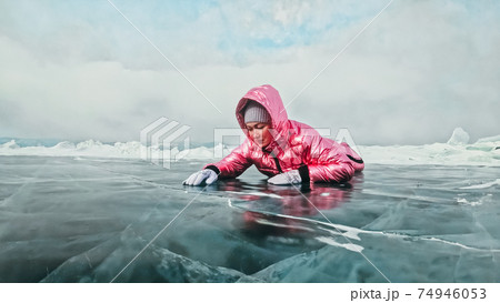 Girl walking on cracked ice of a frozen lake Baikal. Woman trave 74946053