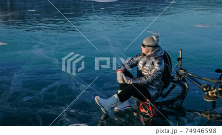 Woman sitting near her bike on ice. The girl cyclist stopped to 74946598