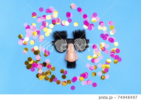 funny face - fake eyeglasses, nose and mustache, confetti, sequins on blue background Happy fools day concept 1st April party Holiday card funny face - fake eyeglasses, nose and mustache, confetti, sequins on blue background Happy fools day concept 1st April party Holiday card 74948497