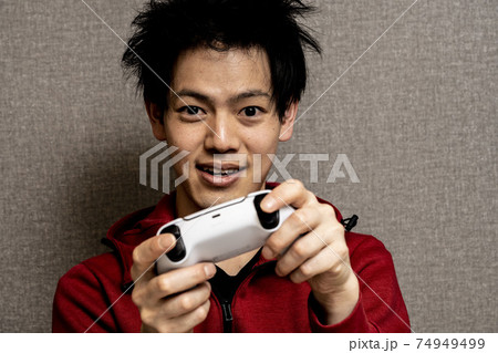 ビデオゲーム中毒の若い男性 寝癖のある若いアジア人男性 ゲームに狂った青年 の写真素材