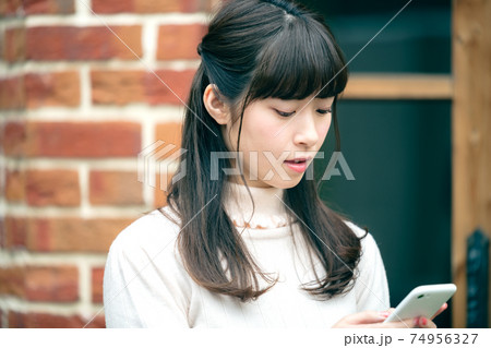 家の前でスマホを操作する若い女性 家の前でスマホを操作する若い女性 74956327