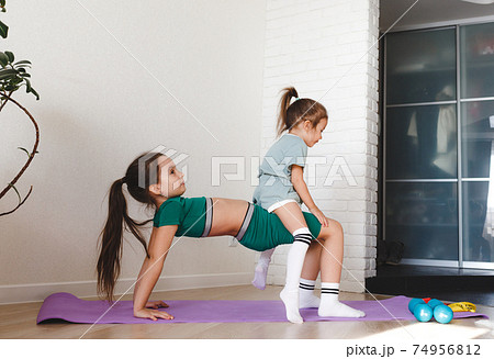 two little girls in sports uniforms are doing fitness at home two little girls in sports uniforms are doing fitness at home 74956812