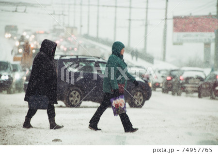 people crossing the road in stormy snowy weather at shallow depth of field people crossing the road in stormy snowy weather at shallow depth of field 74957765