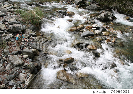 渓流の強い瀬で女性の釣り人がヤマメ イワナを狙って竿を出しているの写真素材