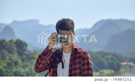 Young man photographing with vintage camera Young man photographing with vintage camera 74965251
