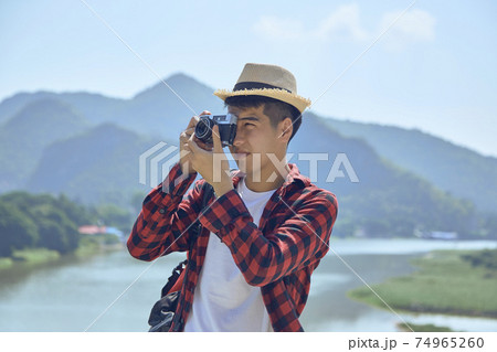 Young man photographing with vintage camera 74965260