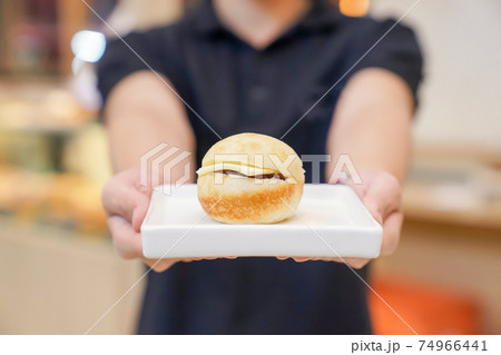 mini hamburger on white ceramic square dish with hand holding. 74966441