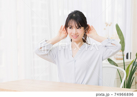 部屋で聞き耳を立てる若い女性 74966896