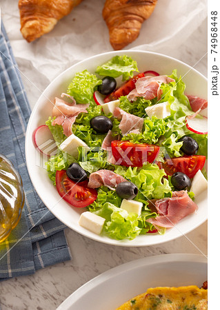 Healthy salad in a bowl with olives, raddishes, tomato, cheese and lean ham served for breakfast 74968448