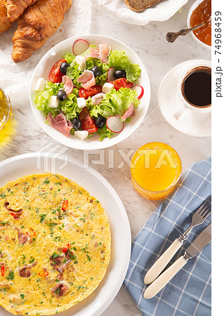 Broad assortment of food including omelette, croissants, salad, bread, coffee and orange juice served on a table Broad assortment of food including omelette, croissants, salad, bread, coffee and orange juice served on a table 74968459