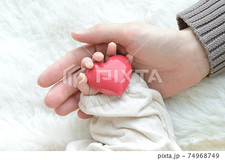 ハートのオブジェをつかむ赤ちゃんの手とママの手 74968749
