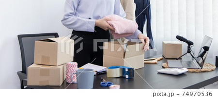 Young Asian women pack their clothes into boxes and prepare them to be delivered by post, Online clothing sales business, Business of selling clothes on social media or selling online. 74970536