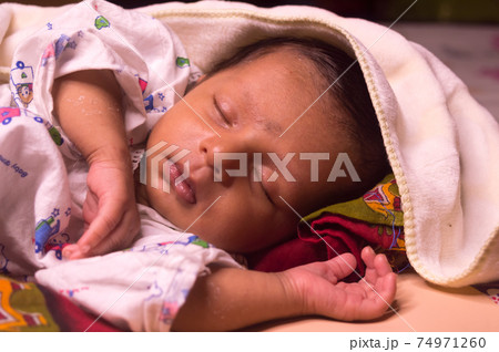 Close up face of cute sleeping newborn baby boy in drowsy eyes with sleepy mood. One month old Sweet infant toddler Closeup portrait. Indian ethnicity. Front view. Child care peace tranquil background 74971260