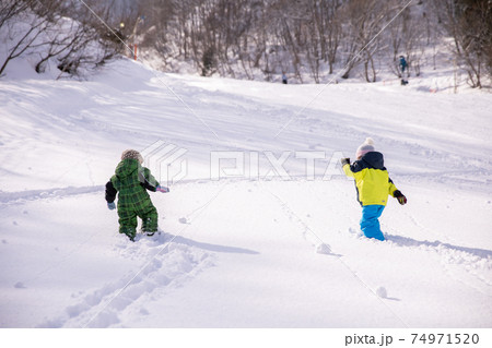 男の子と女の子がスキーウェアーを着てスキー場を登っている Winterの写真素材