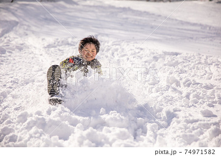 男の子がそりに乗って楽しんで遊んでいる　winter 74971582