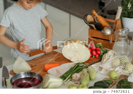 The child puts vegetables on the table and prepares a salad The child puts vegetables on the table and prepares a salad 74972631