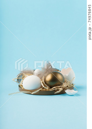 Easter white golden eggs, quail eggs and feathers on blue background. Easter white golden eggs, quail eggs and feathers on blue background. 74976845