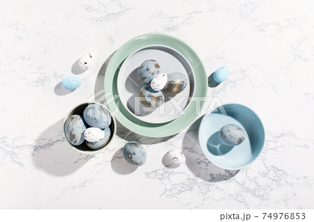 Easter blue golden eggs, quail eggs and plates on gray marble background 74976853