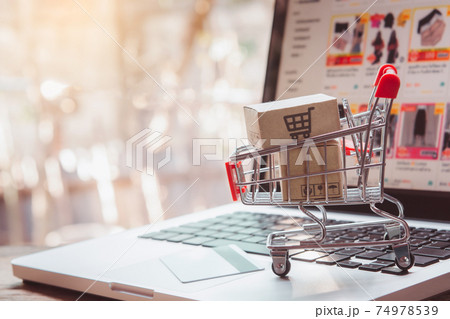 Shopping online. Credit card and cardboard box with a shopping cart logo in a trolley on laptop keyboard. Shopping service on The online web. offers home delivery 74978539