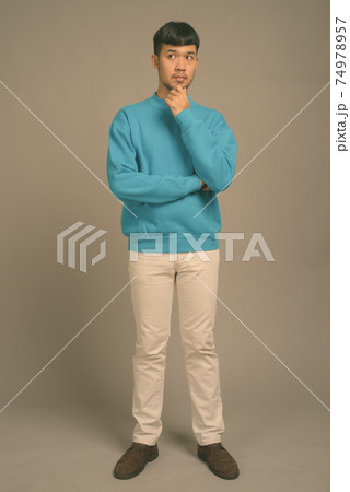 Portrait of young Asian man against gray background Portrait of young Asian man against gray background 74978957