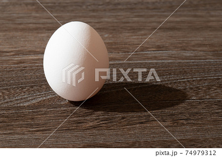 こげ茶色の木製テーブルの上で立っている卵 74979312