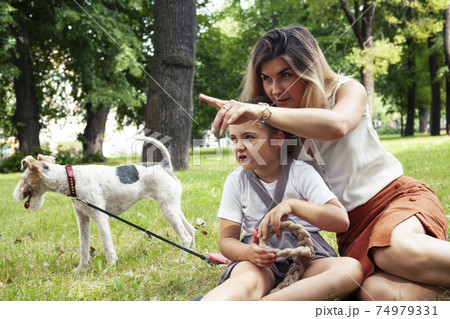 young pretty caucasian mother walking with little cute daughter and dog fox terrier, lifestyle people concept 74979331